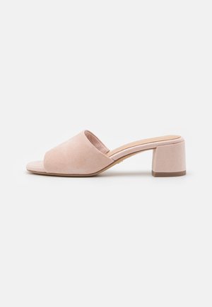 Beige ruskind open-toe mule med bred rem og lav blokhæle på hvid baggrund.