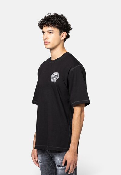 Zwarte katoenen t-shirt met korte mouwen, ronde hals en een witte logopatch op de linkerborst. Heeft contrasterende stikdetails.