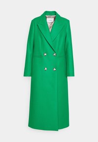 Long manteau en laine vert à double boutonnage, larges revers, boutons argentés, poches latérales et doublure intérieure beige.