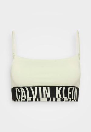 Hele kreemjas bralette reguleeritavate rihmade ja laia musta elastse vööga, millel on valge "CALVIN KLEIN" bränding. Ühtlane tekstuur kogu pinnal.