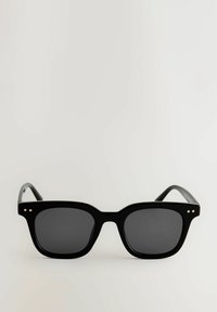 Lunettes de soleil noires avec une monture rectangulaire épaisse, des verres foncés et de subtils accents d'éclats dorés à l'avant. Fini brillant, design moderne.