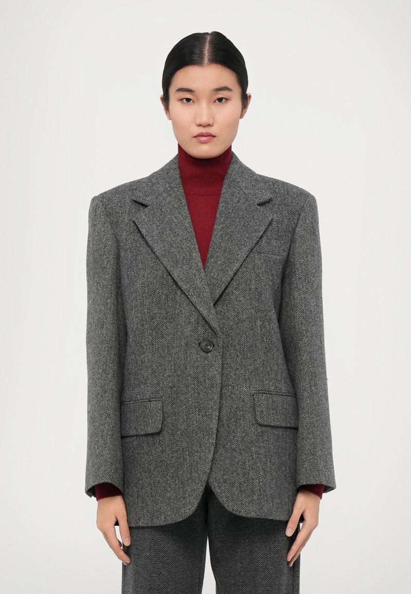 Grå houndstooth-blazer med en ensam knapp, skräddarsydd passform, breda slag och två framfickor, lagd över en vinröd polotröja.