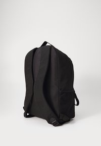 Zaino nero realizzato in stoffa resistente, caratterizzato da una forma arrotondata, spallacci regolabili e una tasca laterale in rete per lo stoccaggio.