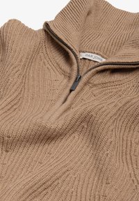 Strikket pullover i lys brun med lynlåskrave, der har strukturerede ribbede mønstre og en blød, vævet finish.