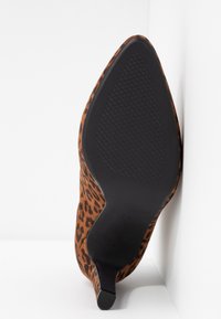 Chaussure à talon haut en imprimé léopard avec un embout pointu, en suède, et une semelle en caoutchouc noir dotée d'un motif de grip texturé.