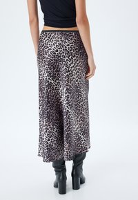 Leopardprint midi rok van lichtgewicht stof, met een luchtige silhouet, voorzien van een zwarte elastische tailleband en een gladde textuur. Gecombineerd met zwarte boots.