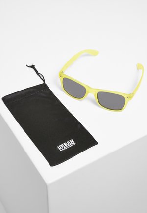 Ochelari de soare galbeni cu lentile gri, forma rectangulară. Include un plic negru cu logo-ul "URBAN CLASSICS" imprimat în alb.