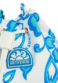 Borsa a sacchetto con coulisse in tessuto blu a fantasia floreale, con un accento in pelle bianca e un'etichetta circolare blu con il logo "SUNDEK."