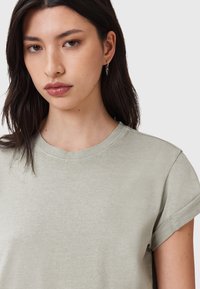 T-shirt grigio chiaro a maniche corte con scollo rotondo, caratterizzato da una texture liscia e dettagli di cucitura discreti sulle maniche.