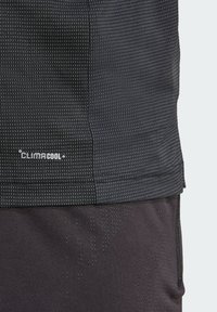 T-shirt de sport noir avec la marque ClimaCool, design texturé avec de petits motifs géométriques, et une finition en tissu lisse.