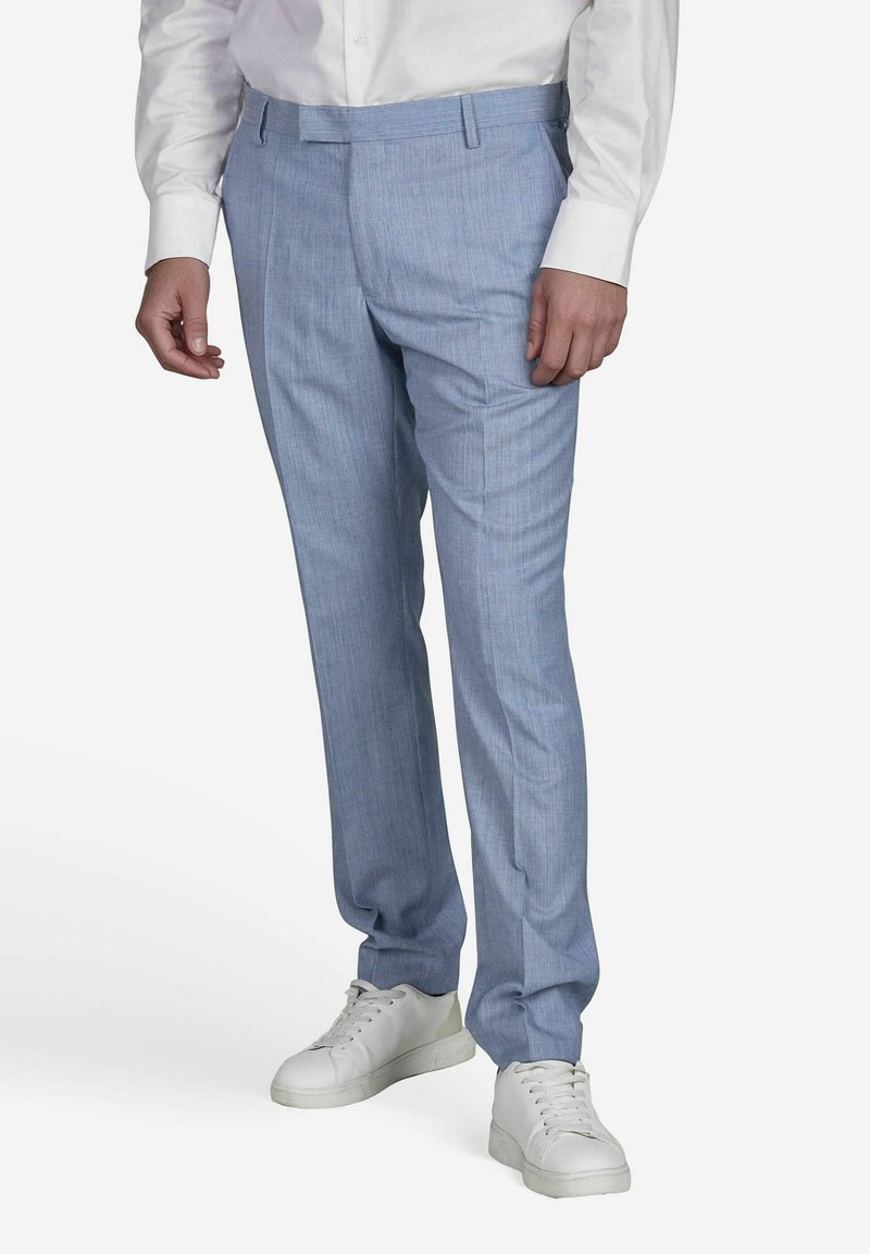 Lichtblauwe op maat gemaakte broek met een fijne textuurpatroon, platte voorkant en zijzakken, gecombineerd met witte sneakers.