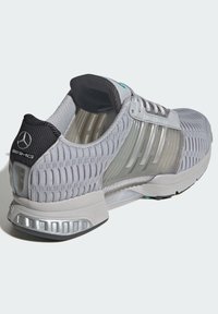 Szare buty sportowe z teksturowaną siateczką na górze, przezroczystymi panelami bocznymi i amortyzującą podeszwą. Posiada czapkę pięty w kolorze czarnym oraz srebrne akcenty.