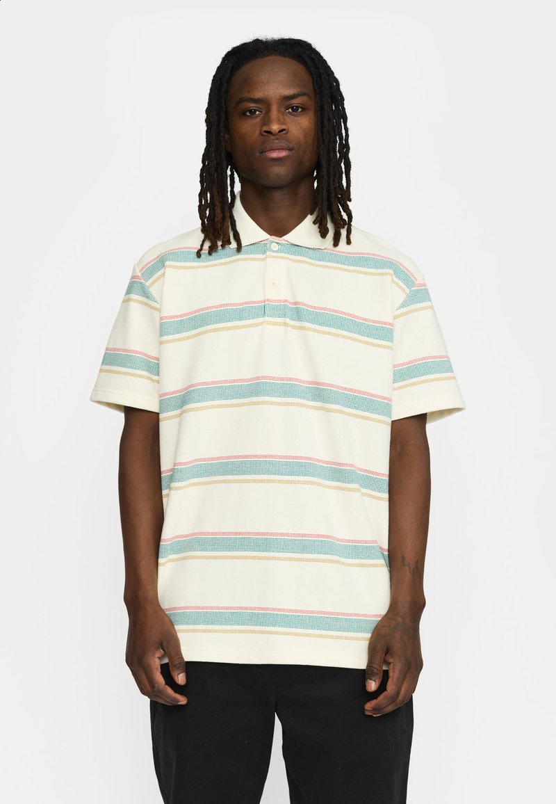 Korte mouwen polo shirt in crème met horizontale strepen in blauw, rood en geel. Beschikt over een geknoopte kraag en een gestructureerde stof.