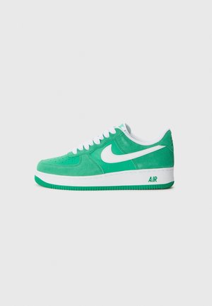 Groene en witte Nike Air Force 1 sneaker met suède en lederen materialen, witte veters en de tekst "AIR" op de zool.