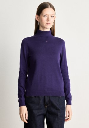 Pulover violet din tricot moale, cu un guler înalt, având tivuri și mansete ribbed. Detaliu mic cu logo în culori contrastante pe piept.