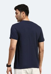 Marineblaue Baumwoll-T-Shirt mit kurzen Ärmeln und rundem Ausschnitt, mit einer lockereren Passform und glatter Textur, von hinten betrachtet.