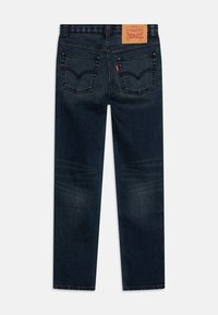 Dark blue denim jeans with a straight leg design, featuring two back pockets, subtle fading, and a leather patch with brand details above the waistband.