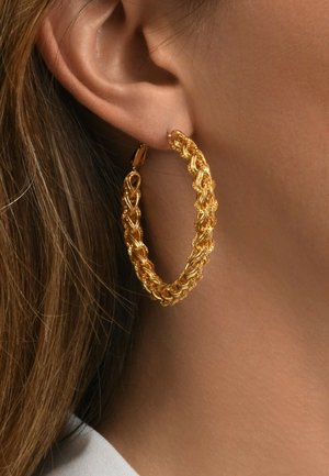 Clou d'oreille en métal doré avec un design en corde tressée. Présente une finition polie et un fermoir sécurisé, mettant en valeur des détails et des textures complexes.