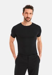 Black short-sleeve crew neck t-shirt made of smooth fabric, fitted design, displayed on a man with a well-defined physique.