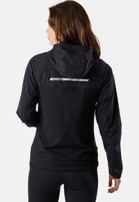 Zwarte waterdichte jas met een capuchon, voorzien van een reflecterend logo en een sleek ontwerp. Soepele textuur met lange mouwen en verstelbare manchetten.