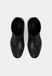 Botas de tornozelo pretas com um acabamento liso e brilhante, ponta afilada e fecho com zip, apresentando um design elegante e minimalista.