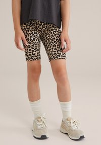 Leopardmönstrade cykelshorts i beige och svart, lätt och stretchigt tyg. Matchas med vita randiga strumpor och krämfärgade sneakers för kontrast.