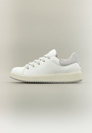 Zapatilla blanca de caña baja con cordones grises, cuello acolchado en el tobillo y suela acanalada en color blanco roto sobre un fondo neutro.