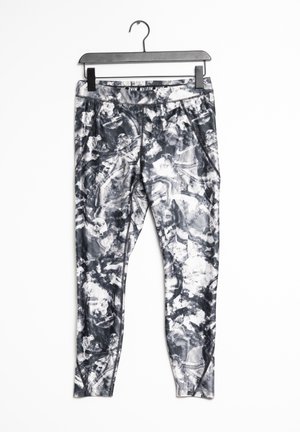 Czarno-białe legginsy Nike z abstrakcyjnym wzorem zawieszone na czarnym wieszaku z widocznym logo na lewym udzie.