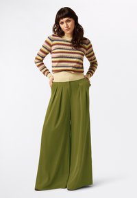 Leichtes, gestreiftes Sweater in Erdtönen, kombiniert mit hoch taillierten, fließenden, olivgrünen Plisseehosen, beide mit einer lässigen Passform.