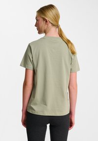 Ljust grön bomullströja med klassisk rund halsringning och korta ärmar, visad bakifrån. Slät textur med rak nederkant.