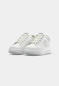 Et par hvite skinnsneakers fra Karl Lagerfeld med tykke såler, snøring og merkevarelogo på sidene og tungen, vist mot en hvit bakgrunn.