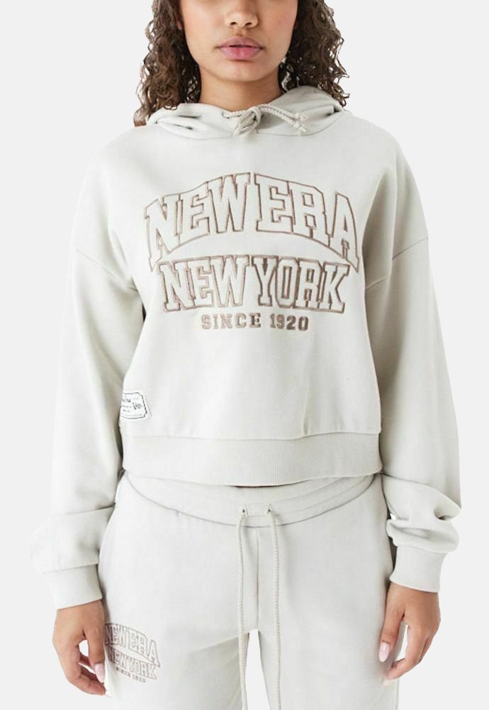 Felpa corta grigia chiara con cappuccio regolabile, caratterizzata dalla scritta "NEW ERA NEW YORK" in grassetto color crema e un tessuto testurizzato.