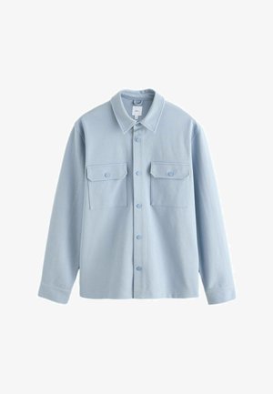Světle modrá košile s dlouhým rukávem, zapínání na knoflíky a dvěmi knoflíkovými klopovými kapsami na hrudi, střední velikost, strukturovaná látka.