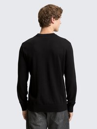 Pull en maille noire à manches longues, poignets et ourlet côtelés, présentant un design simple. Texture douce et coupe standard vue de dos.