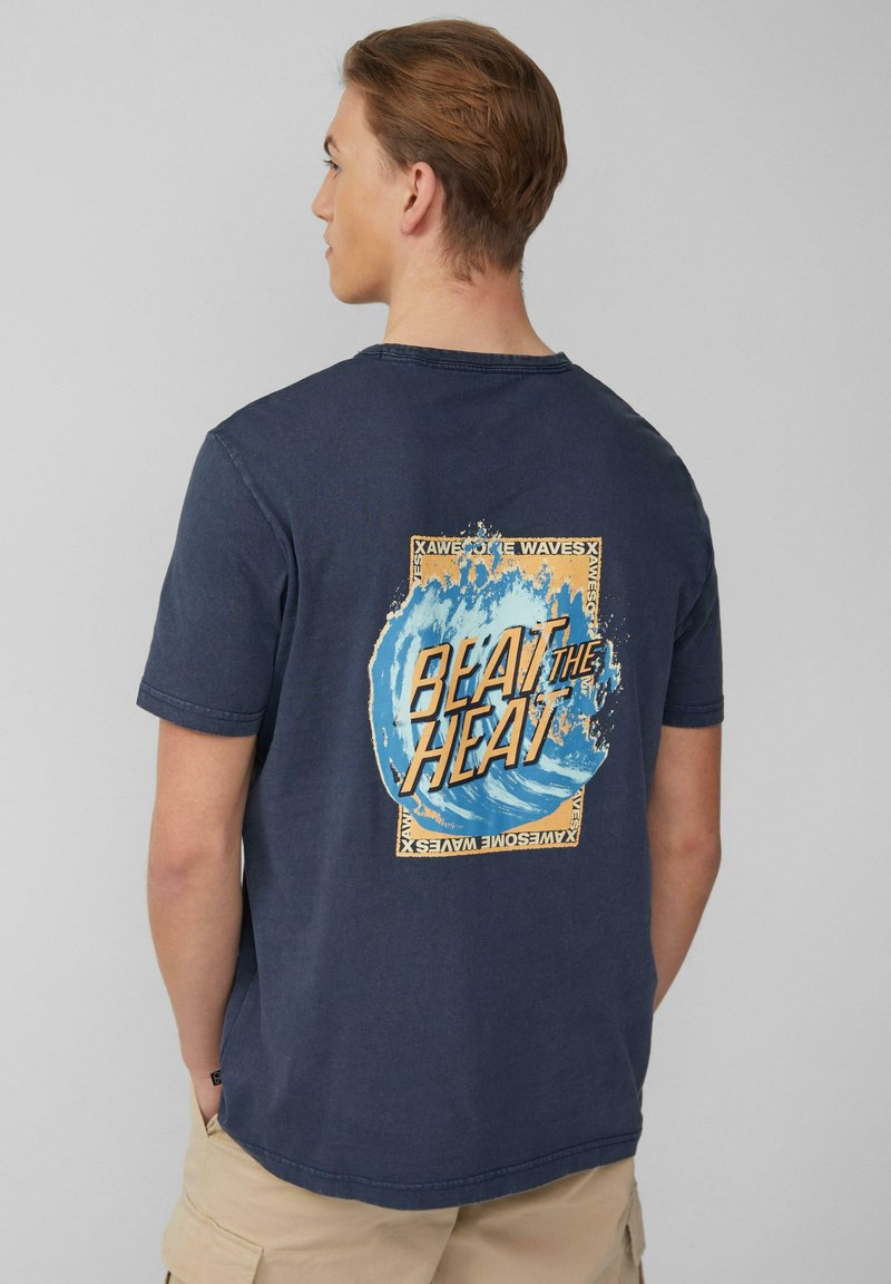 Marineblauwe katoenen t-shirt met een grote grafische afbeelding op de achterkant: blauwe golven met de tekst "BEAT THE HEAT" in dikke, oranje letters.