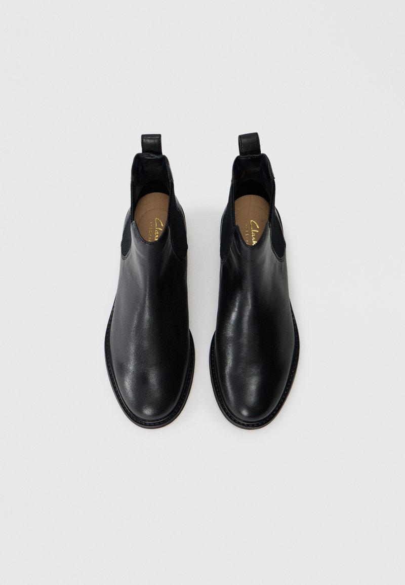 Schwarze Lederstiefeletten mit glatter Oberfläche, elastischen Seitenpanels und Ziehschlaufen für ein einfaches Anziehen. Runde Zehen und gestickte Details rund um die Sohle.