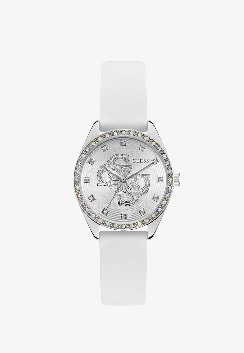 Montre-bracelet à bracelet blanc avec lunette en argent ornée de cristaux, cadran argenté avec des marqueurs d'heure en cristal et des logos "G" superposés, nom de la marque GUESS.
