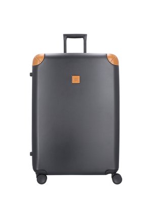 Maleta negra de concha dura con acentos de cuero marrón claro, textura suave, forma rectangular, asa retráctil y cuatro ruedas para movilidad.