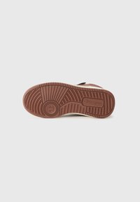 Suela de zapatilla de goma marrón con patrón de tread texturizado. Media suela blanca y detalle del logotipo "Champion" en relieve cerca del talón. Diseño plano y ancho.