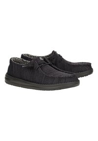 Schwarze Strickslipper mit strukturierten Oberflächen, schwarzen Gummisohlen und passenden schwarzen Schnürsenkeln. Das Innere verfügt über ein kontrastierendes, gemustertes Futter.