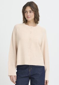 Cardigan tricotat roz deschis cu decolteu rotund, închidere cu cinci nasturi și manșete striate. Purtați peste blugi din denim închis la culoare.