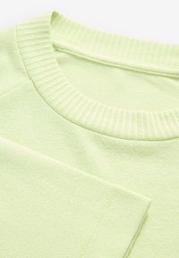 Light green cotton T-shirt with a ribbed crew neckline and short sleeves, featuring a smooth texture and clean stitching details.