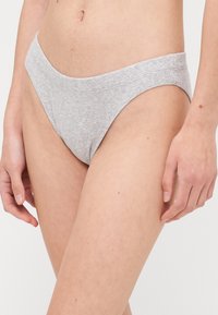 Grå ribbede bomullsbikini-truser med lavt liv og sømløse sider, som har en glatt tekstur og minimalistisk design.