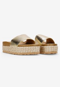 Sandalias de slide metálicas doradas con una tira ancha, plataforma envuelta en yute y superficie texturizada; suela ligera para mayor tracción.