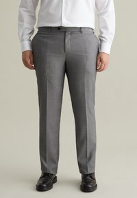 Grijze op maat gemaakte broek van textuurstof, met een platte voorkant, zijzakken en een klassieke pasvorm. Draag met zwarte schoenen.