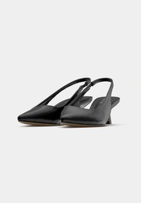 Μαύρα παπούτσια slingback με μυτερές μύτες, γυαλιστερή υφή και μικρό τακ ούνι. Διαθέτουν απλό σχέδιο και λεπτομέρεια διακριτικής ραφής.