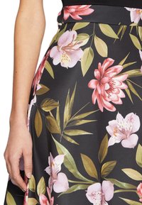 Floral skirt featuring large pink and white flowers and green leaves on a black background, with a smooth fabric texture and fitted waistband.