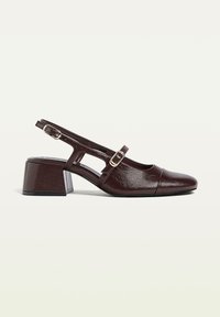 Ruskea nahkainen slingback-kengä, jossa on neliön muotoinen kärki, matala lohkokorko ja säädettävä solkihihna. Teksturoitu pinta, jossa on leikattu muotoilu sivuilla.