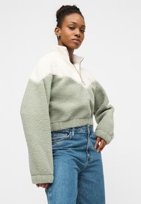 Πουλόβερ από φλις με μερικό φερμουάρ, διαθέτει σχέδιο με μπλοκ χρωμάτων σε μέντα πράσινο και κρεμ, φαρδιά μανίκια και υφή απαλή και ανάγλυφη.