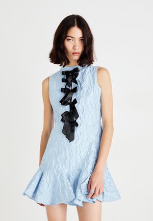 Robe sans manches bleu clair avec un tissu texturé, présentant un ourlet froncé et des nœuds en satin noir le long du dos. Surface lisse et dévoilant un motif.